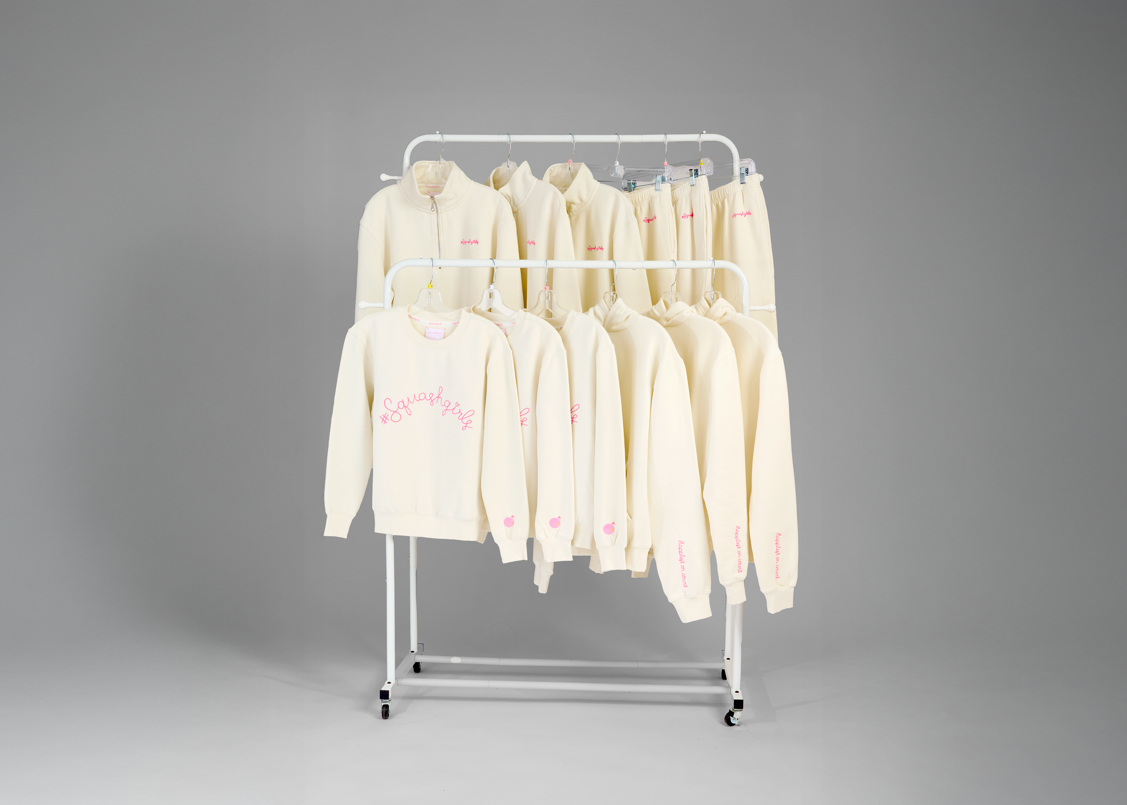 White sweatshirts on a metal rack against a gray background