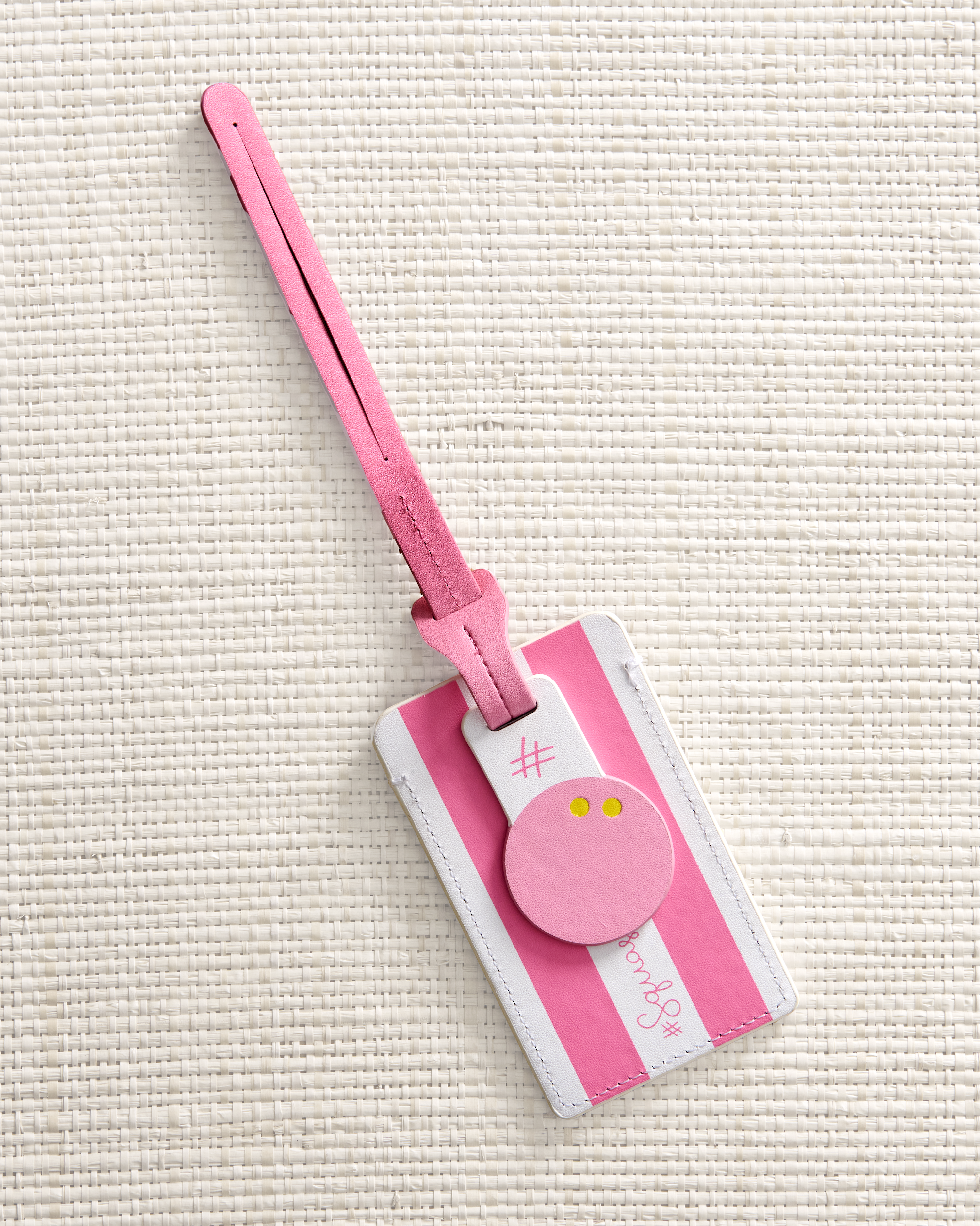 Pink luggage tag with a squash ball tag, textured beige background
